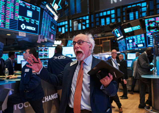 White-haired trader on lively stock exchange floor.