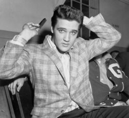 Young man styling hair; plaid and letterman jackets.