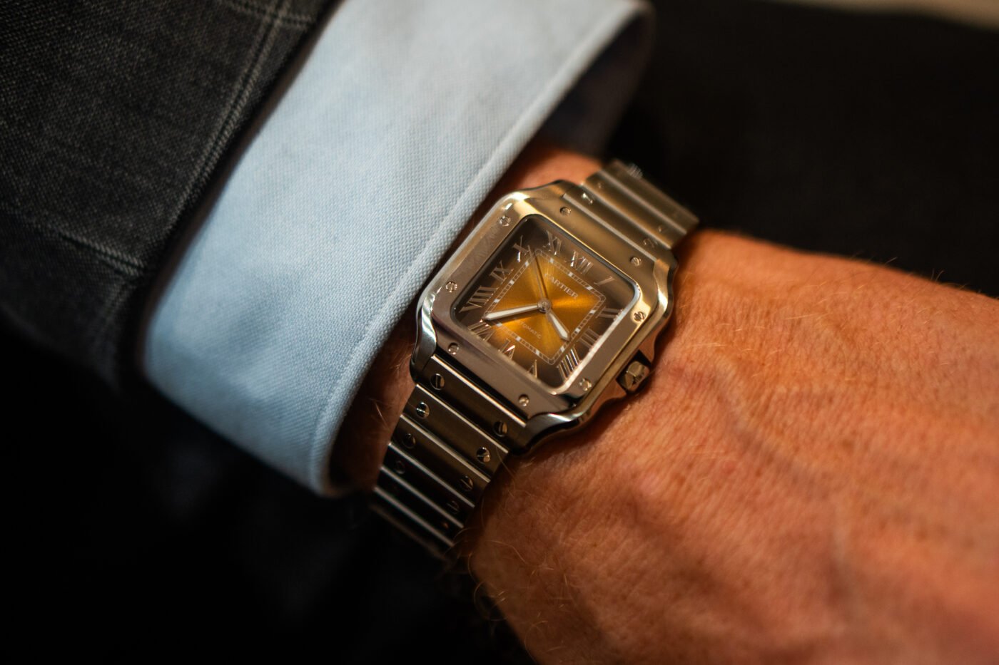 Luxury silver watch with orange dial worn.