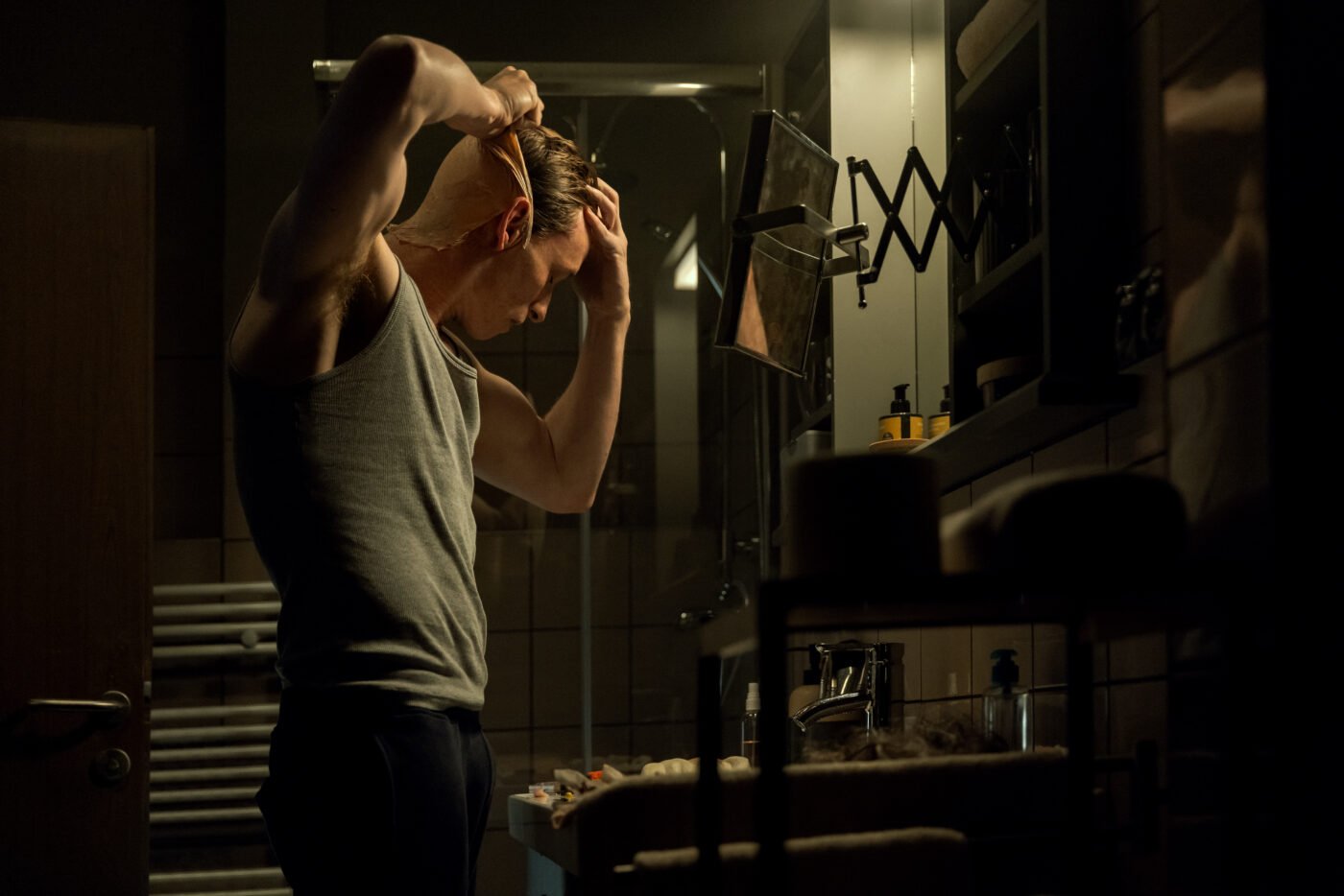 Eddie Redmayne in The Day Of The Jackal In dim bathroom