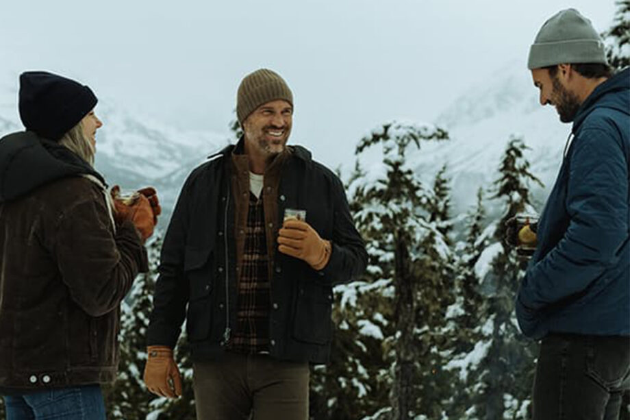 Three people in winter wear discussing sales.