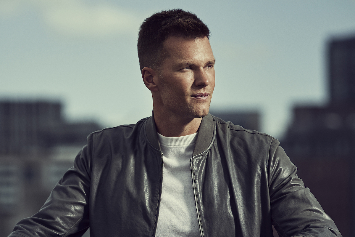 Person in gray jacket and white shirt outdoors.