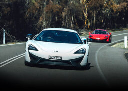 A white McLaren races a red sports car.