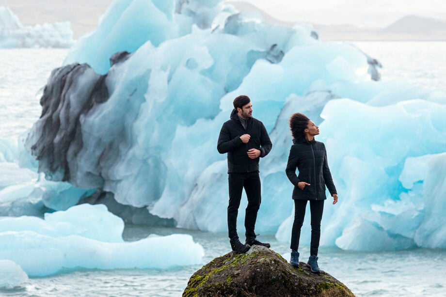 Two men in jackets by icebergs, winter scene.