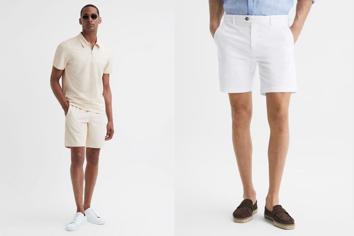 Two mean wearing smart casual outfits with shorts. One wears an off-white polo with off-white shorts. The other wears a blue shirt tucked into white shorts.