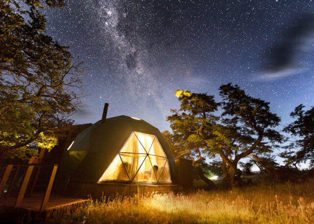 Glowing geodesic dome glamping under Milky Way.